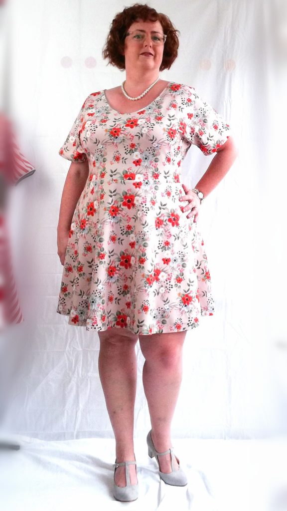 Suzanne in een jurk met bloemenprint, één hand op haar heup